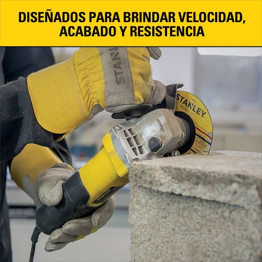 A close-up of a person wearing work gloves operating a yellow Stanley angle grinder to cut or grind a concrete block. The text above reads: 'Designed to provide speed, finish, and resistance.'
