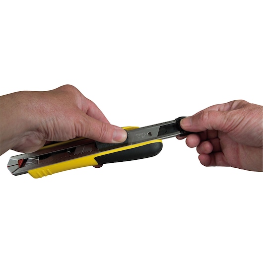 Photo of STANLEY 10-481 utility knife being handled, yellow and black body, close-up on white background.