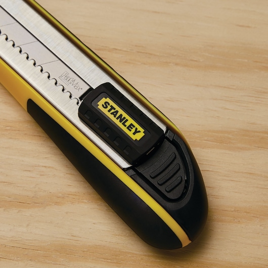 Stanley 10-486 retractable utility knife close-up, yellow and black handle, on wood surface.