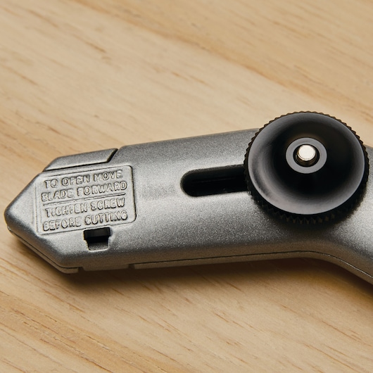 STANLEY 10-525 utility knife handle close-up showing adjustment screw and engraved instructions on wood surface.