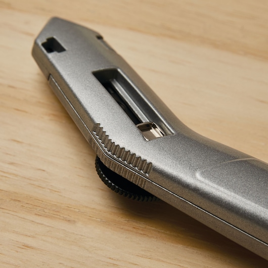Stanley 10-525 utility knife close-up, metallic finish, angled view, on wooden surface.