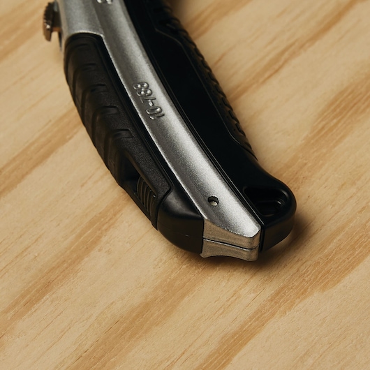 STANLEY 10-788 utility knife handle, black and silver, close-up on wood surface.