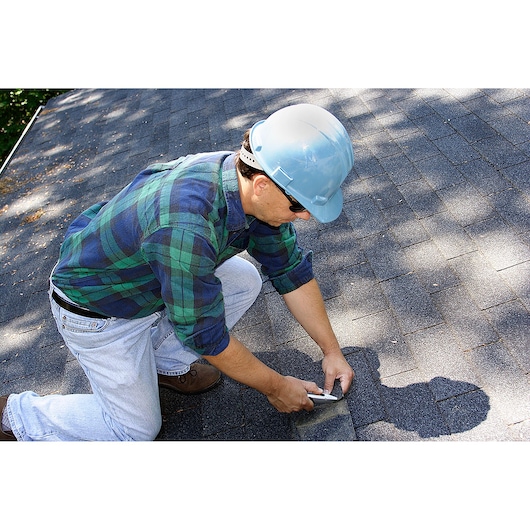 STANLEY 10-789 utility knife in use on roof shingles, person kneeling and cutting roofing material.
