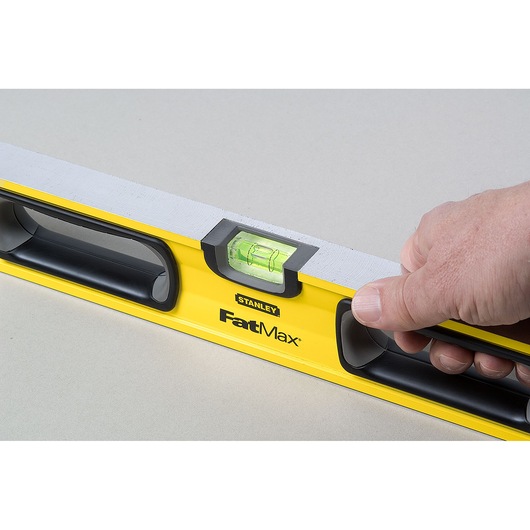 Photo of STANLEY 43-524 FatMax spirit level held in hand, yellow body with black handles and visible vial.
