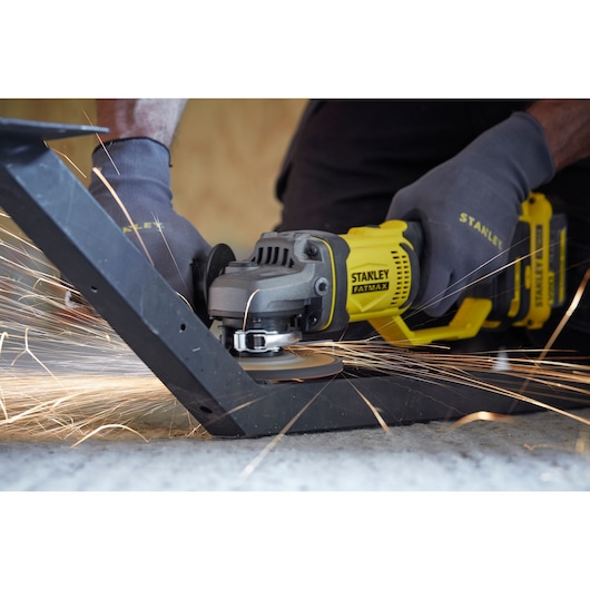 STANLEY SCG400M2K-KR angle grinder cutting metal with sparks, close-up action shot, worker wearing gloves.
