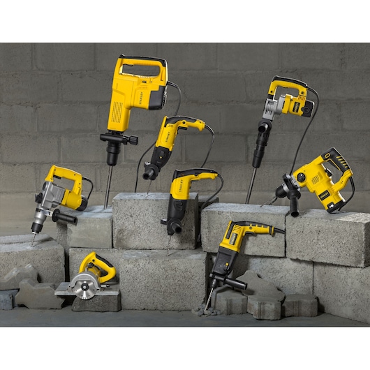 Photo of STANLEY SHR263K-BR power tools, including drills and saws, displayed on concrete blocks.