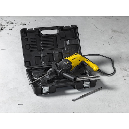 STANLEY SHR263K-BR rotary hammer drill with yellow and black body, carrying case, and accessories displayed on concrete.