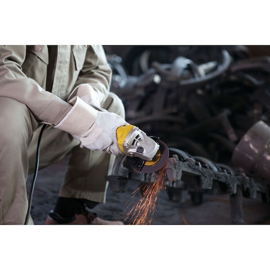 STANLEY STGS8115 angle grinder in use, worker cutting metal with sparks, close-up view.
