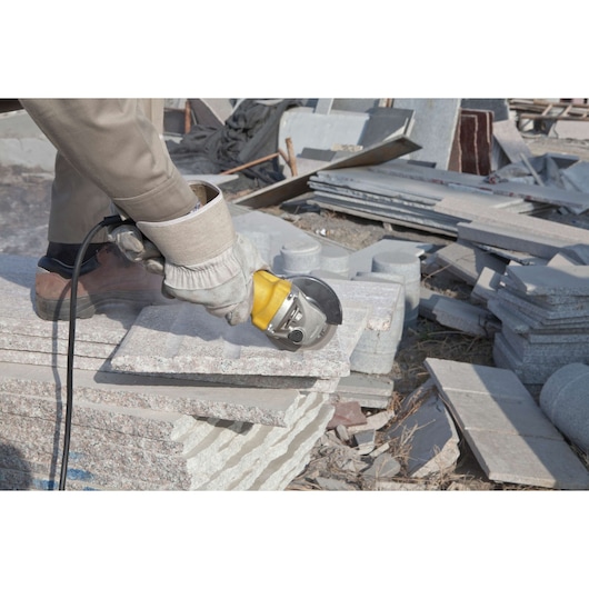 STANLEY STGS8115 angle grinder cutting stone slabs, close-up in outdoor construction setting.