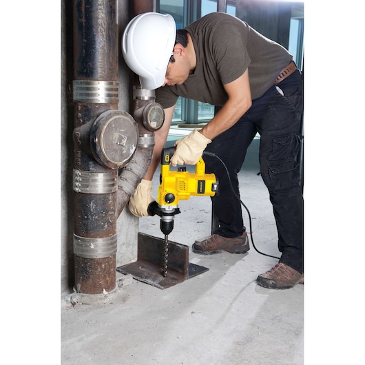 STANLEY STHR1232K rotary hammer drill used on metal beam by worker with gloves and hard hat.