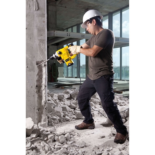 STANLEY STHR1232K rotary hammer drill used on concrete wall at construction site, side view.
