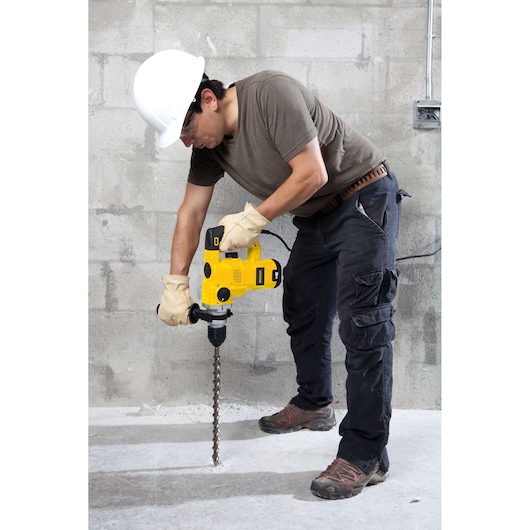 Photo of STANLEY STHR1232K rotary hammer drill in use on concrete floor, construction worker holding tool.