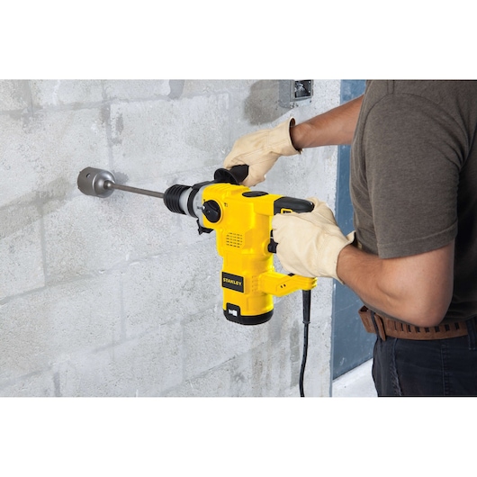 STANLEY STHR1232K rotary hammer drill in use on concrete wall, side view, product held with both hands.