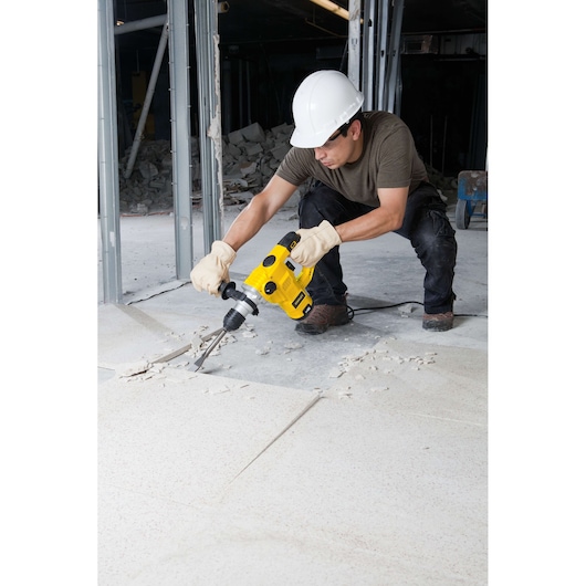 STANLEY STHR1232K hammer drill in use, breaking floor tiles on a construction site.