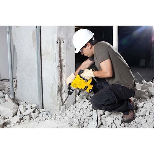 STANLEY STHR1232K rotary hammer in use on concrete pillar, jobsite setting, worker wearing safety gear.