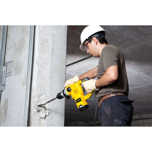 STANLEY STHR1232K rotary hammer drill in use on concrete wall at construction site.