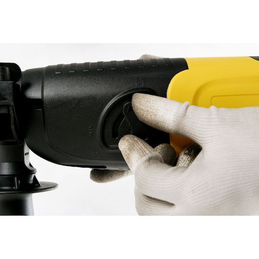 Photo of STANLEY STHR202K rotary hammer mode selector being adjusted with gloved hand, close-up angle.