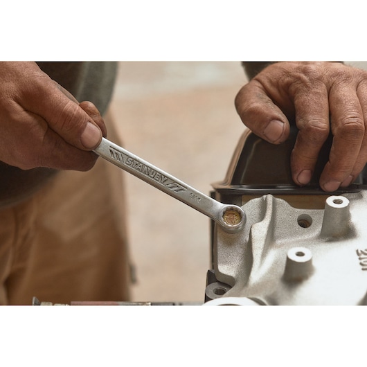 STANLEY STMT72834 wrench in use, close-up photo of hand turning bolt on machinery.