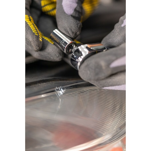 STANLEY STMT82828-LA socket being used with a ratchet, close-up of gloved hands in automotive setting.