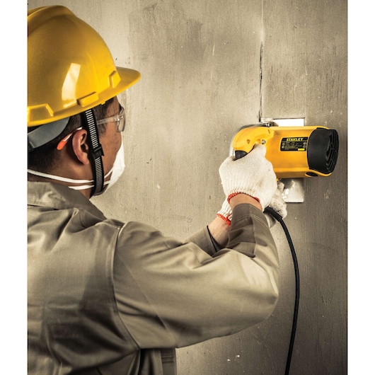 STANLEY STSP125K wall cutter in use by worker in safety gear, cutting vertical line on concrete wall.