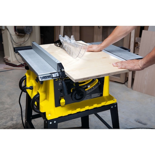 STANLEY STST1825 table saw in use cutting plywood, yellow base, photographed from side angle in workshop.