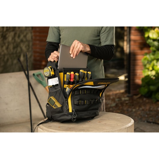 Photo of STANLEY STST515155LA tool backpack with tools and laptop, indoor setting, front angle.